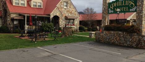 A stone building with a red roof, a sign reading "Phillips Motel", and outdoor seating.