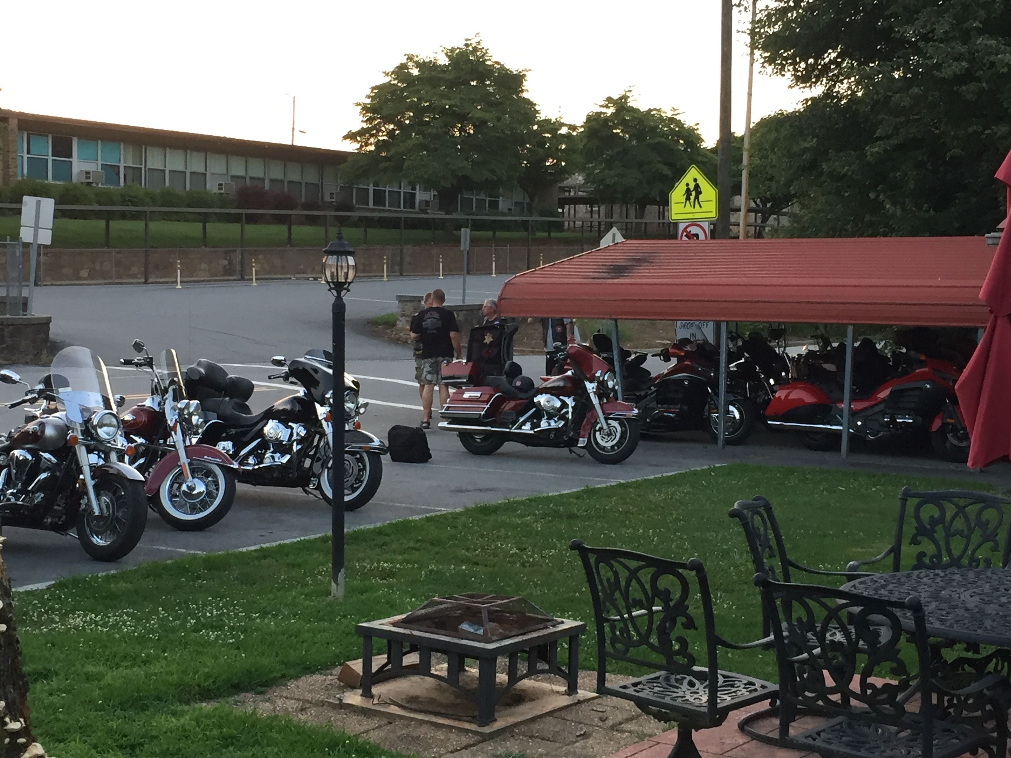 A parking area with motorcycles, a covered seating area, and a pedestrian crossing sign.
