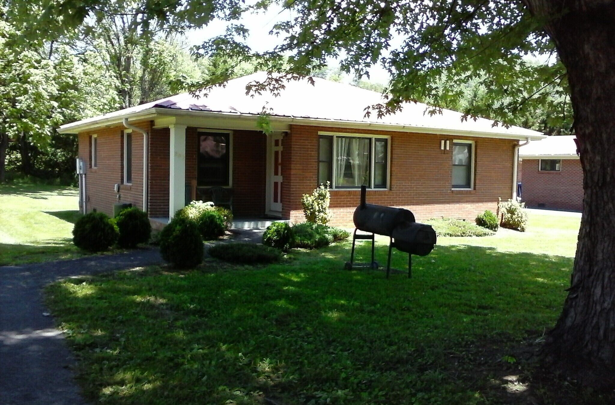 A single-story brick house with a front porch, a mailbox, and a lawn.