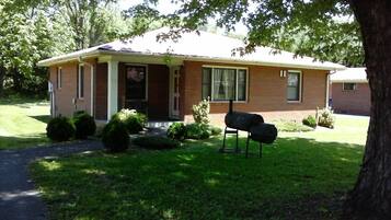 A single-story brick house with a front porch, a mailbox, and a lawn.