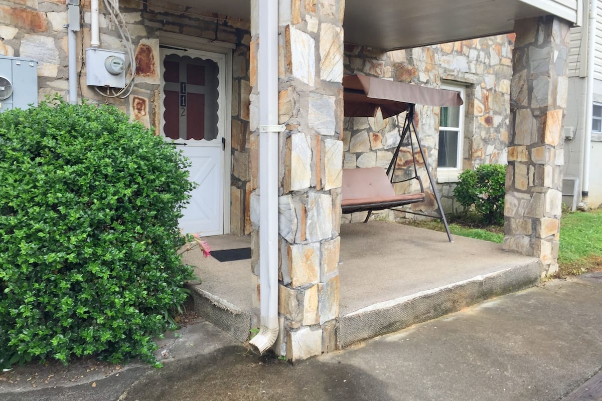 A stone house with a porch, a swing, and a mailbox.