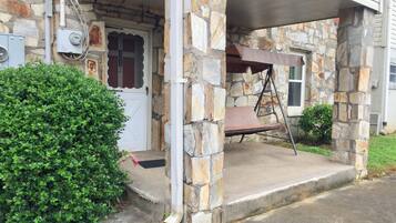 A stone house with a porch, a swing, and a mailbox.