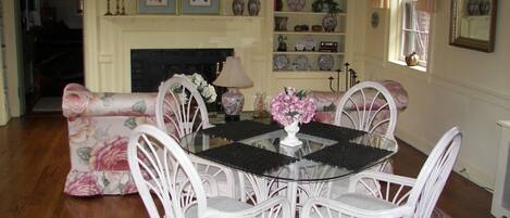 A dining area with a round table, white chairs, and a floral sofa.