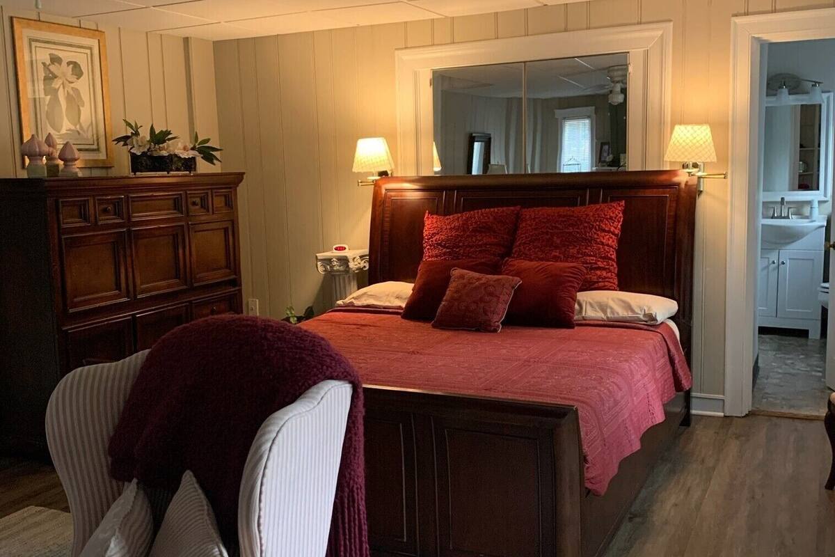 A bedroom with a wooden bed, a nightstand, a dresser, and a chair.
