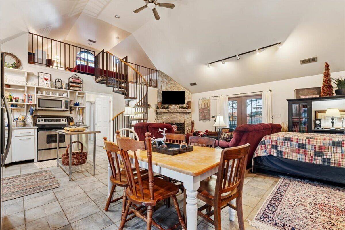 A spacious loft-style living area with a dining table, chairs, a fireplace, and a kitchen with modern appliances.
