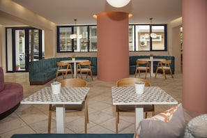 A modern interior with teal sofas, wooden tables, and a large central pillar. - Aquarius Boutique Hotel (Rethymno)