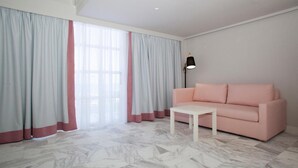 A modern living room with a pink sofa, a white coffee table, and light grey curtains. - Aquarius Boutique Hotel (Rethymno)