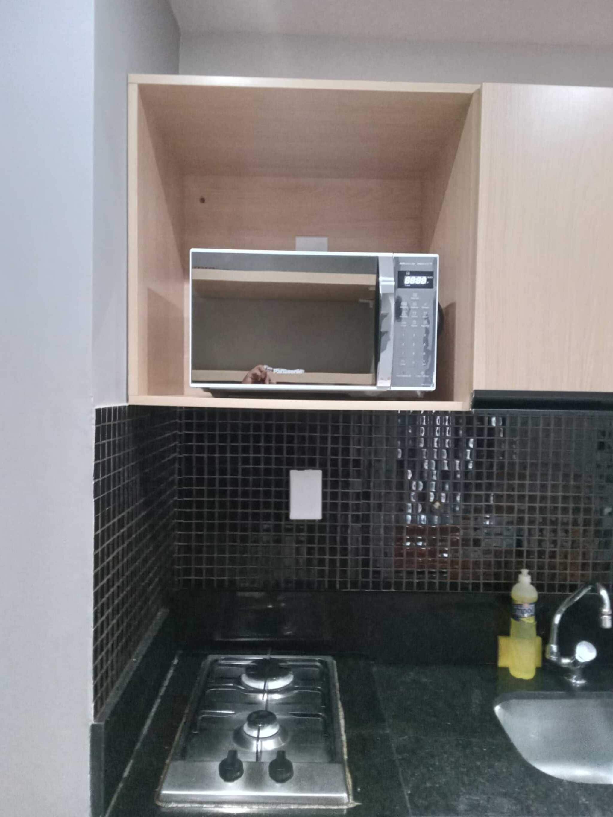 Una cucina con un forno a microonde, un fornello e un lavello.