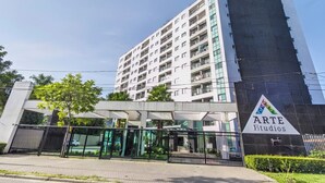 Un edificio de varios pisos con un diseño arquitectónico moderno, que presenta fachada de vidrio y una entrada destacada con una reja metálica.