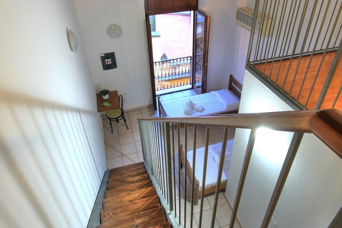Un escalier en bois avec des rampes en métal menant à un balcon.