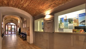 A reception area with a brick ceiling, tiled floor, and a counter displaying hostel information. - Ostello Cagliari (Cagliari)