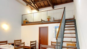 A room with a wooden staircase, a loft area, and a bed with a wooden frame. - Ostello Cagliari (Cagliari)