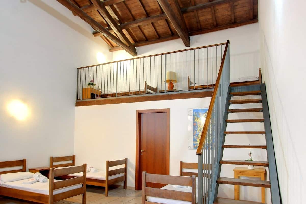 Une pièce dotée d’un escalier en bois, d’un espace en mezzanine et d’un lit avec un cadre en bois.