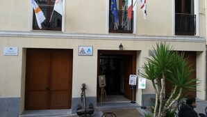 A building with a sign indicating it is a hostel marina. There are flags from various countries, a wooden door, and a small easel with a poster. - Ostello Cagliari (Cagliari)