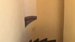 A narrow stairway with a small window and a circular light fixture.
