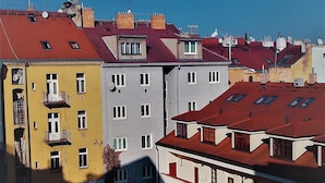 A row of multi-story buildings with red and yellow facades, balconies, and a clear blue sky.