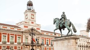 Un edificio histórico con una torre de reloj y una estatua de una figura a caballo.