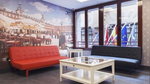 Un vestíbulo de hotel con un sofá rojo, un sofá negro y una mesa de centro de vidrio.