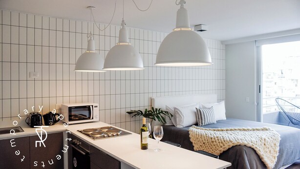 Une cuisine moderne équipée d’un four à micro-ondes, d’un grille-pain et d’une cuisinière, un lit avec vue et des luminaires suspendus.