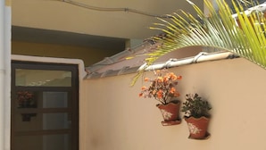 Un bâtiment avec un sol carrelé, une porte fermée et deux plantes en pot accrochées au mur.