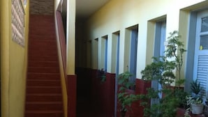 Un couloir avec un escalier, des plantes en pot et un sol carrelé.