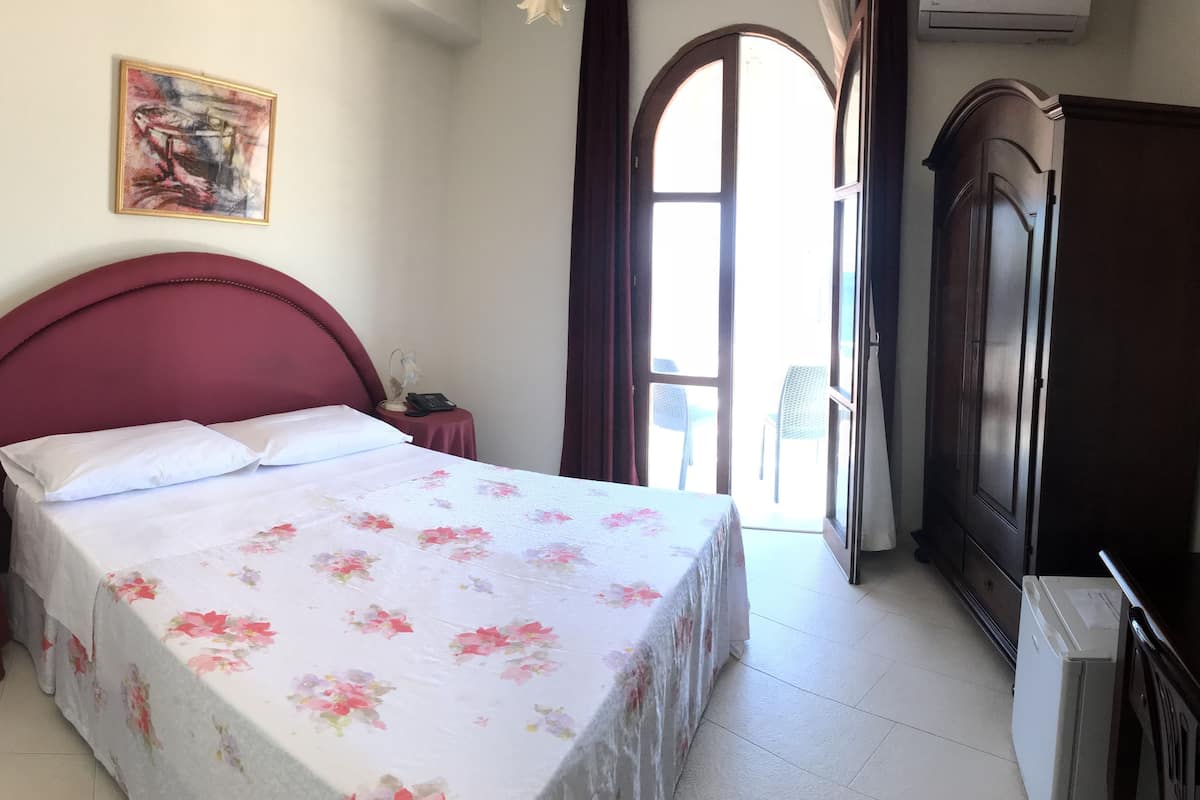 Une chambre à coucher comprenant un lit, une table de chevet, un bureau, une armoire et un tableau accroché au mur.