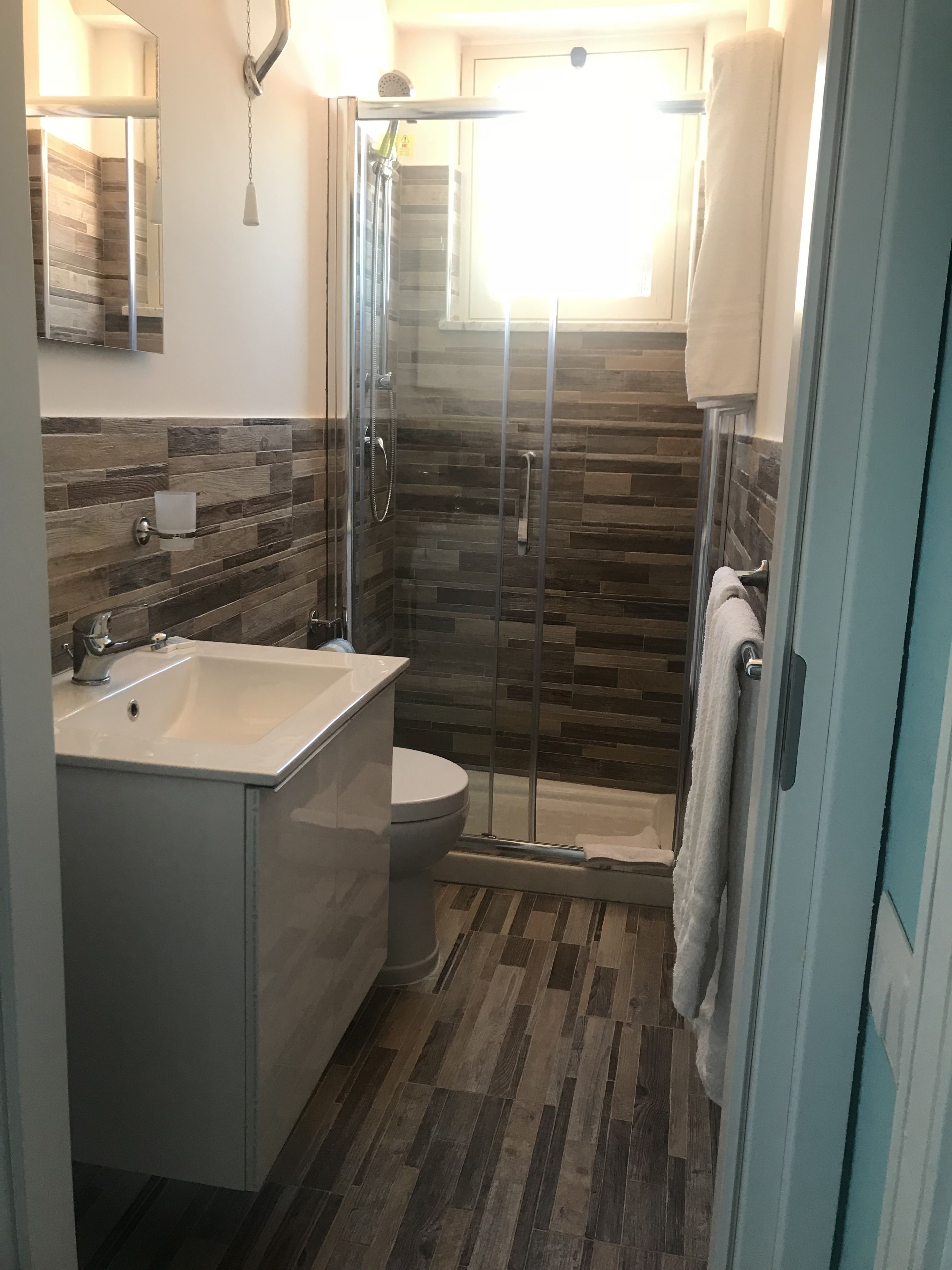 A modern bathroom with a glass-enclosed shower, a sink, and a toilet.