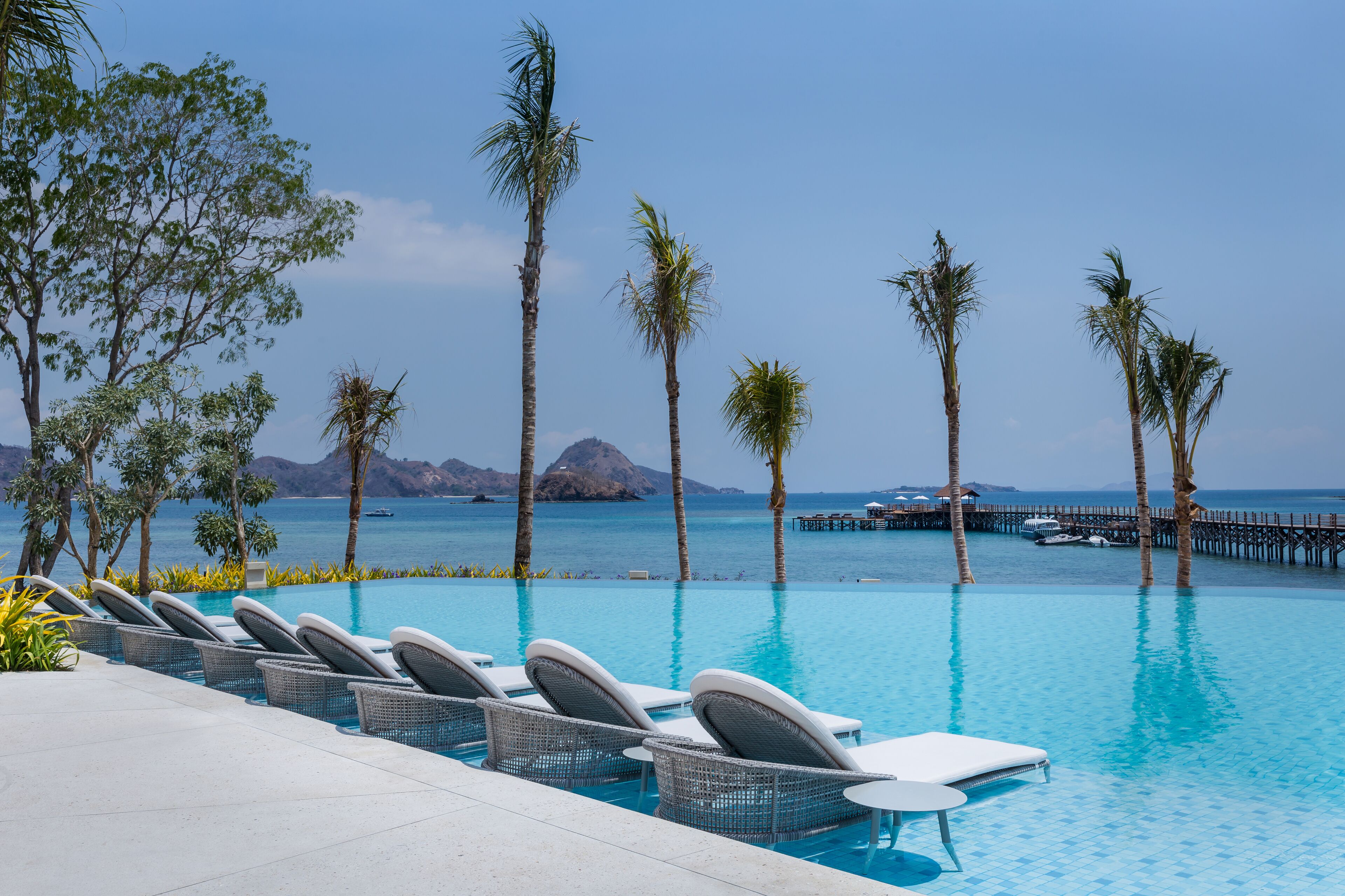 A poolside area with lounge chairs and a view of the sea.