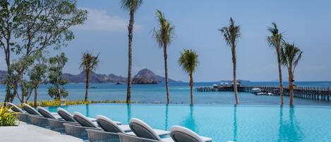 A poolside area with lounge chairs and a view of the sea.