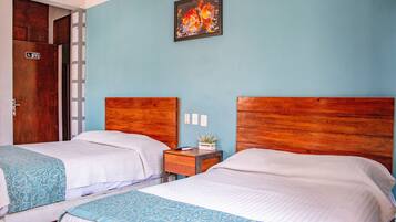 Two single beds with wooden headboards in a room with light blue walls.