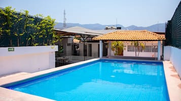 Una piscina al aire libre, sillones reclinables de piscina