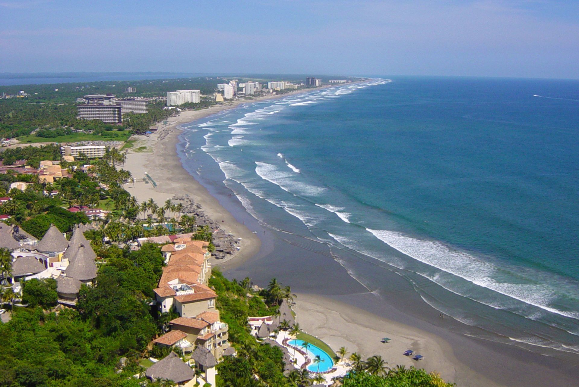 A coastal resort with beachfront properties, a swimming pool, and a view of the ocean.