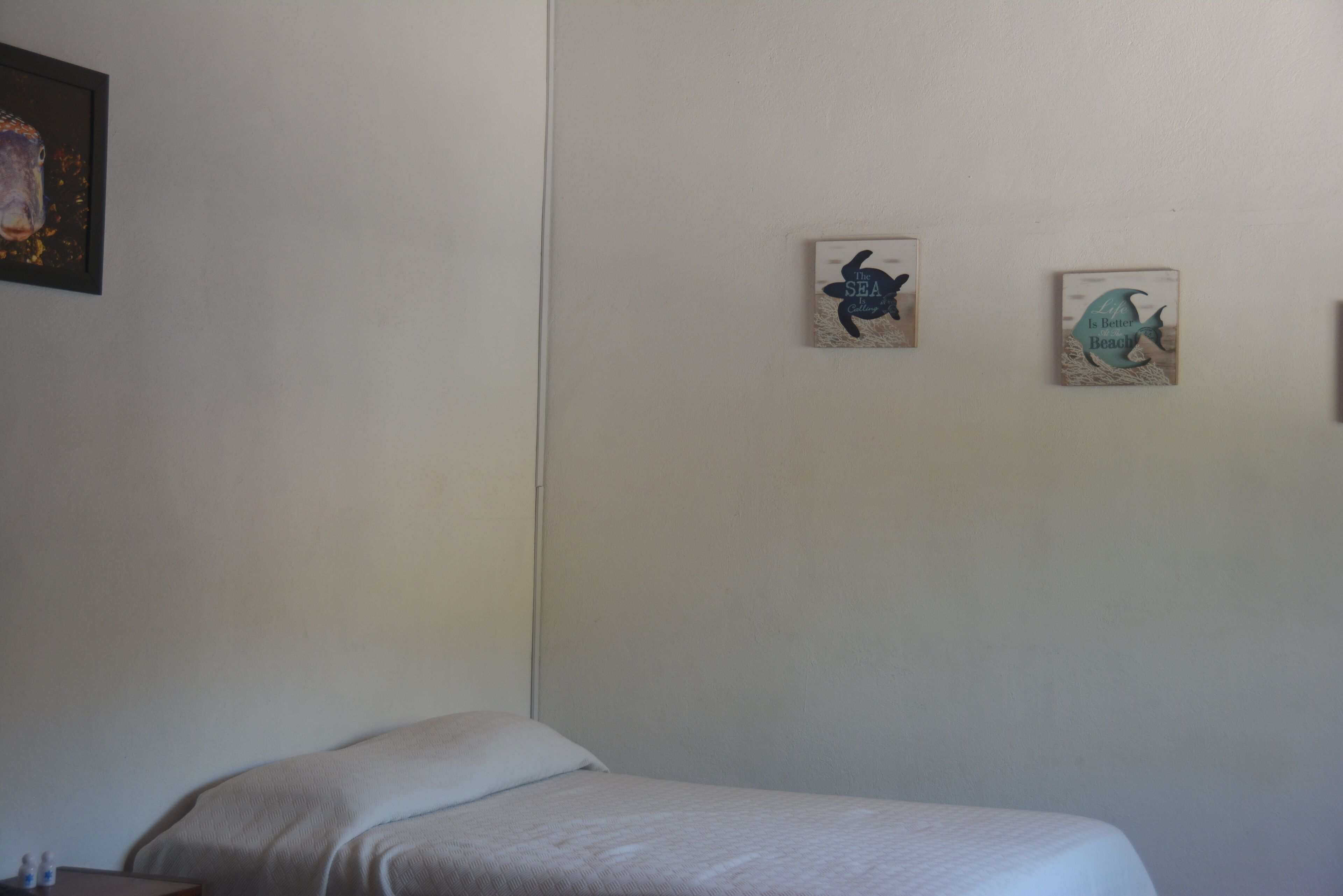 Un dormitorio con cama, mesita de noche y dos adornos de pared.