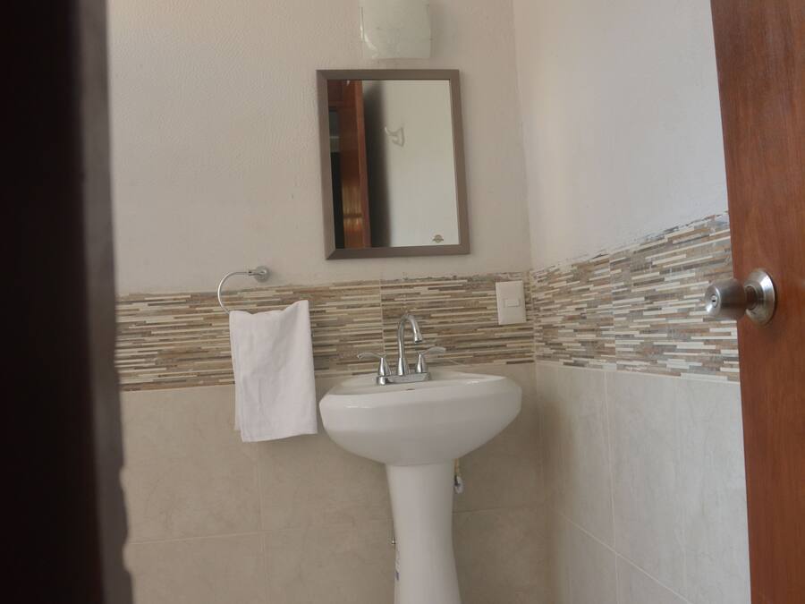 Un baño con lavabo, espejo y perchero para toallas.
