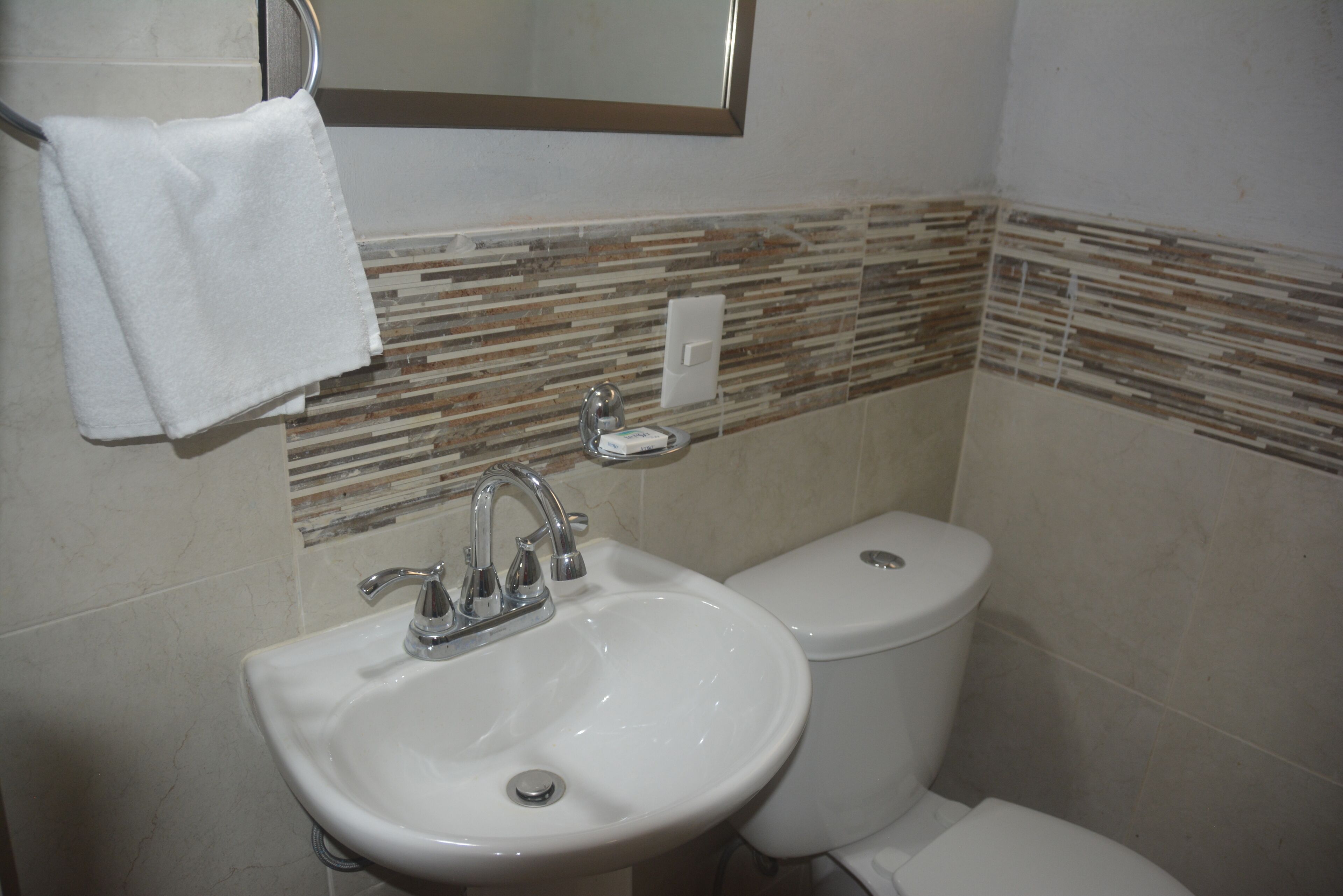 A bathroom with a white sink, a toilet, and a towel hanging on a rack.