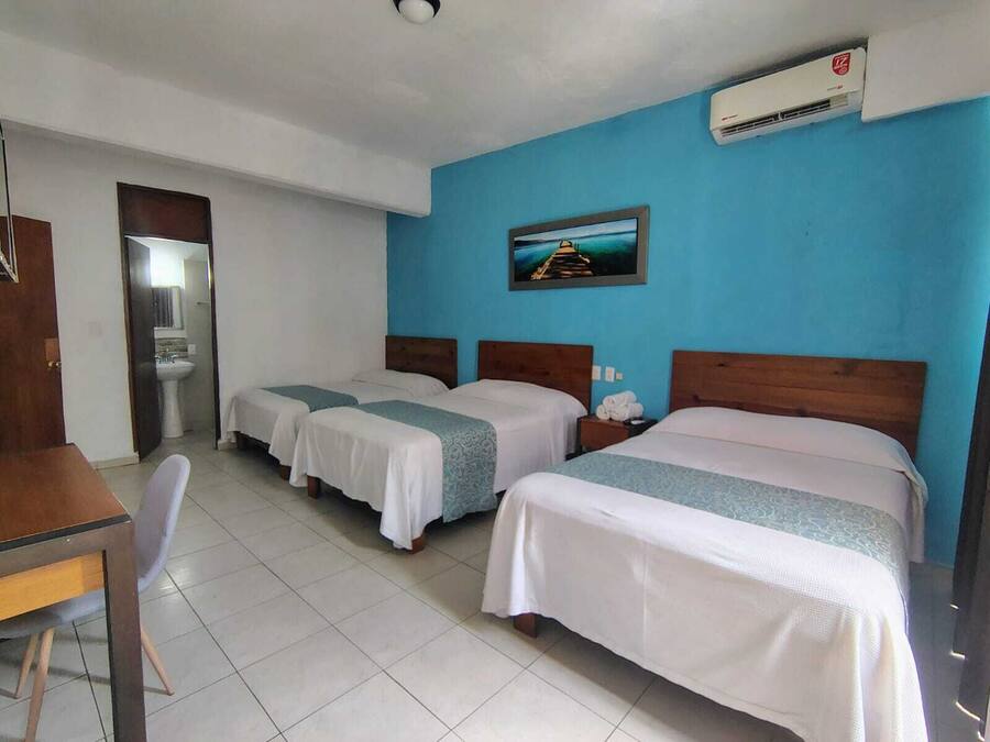 Habitación de hotel con dos camas, un escritorio, una silla, un lavamanos y un equipo de aire acondicionado.
