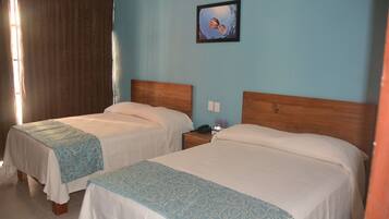 Two single beds with wooden headboards, a nightstand with a phone and a small vase, and a painting on the wall.