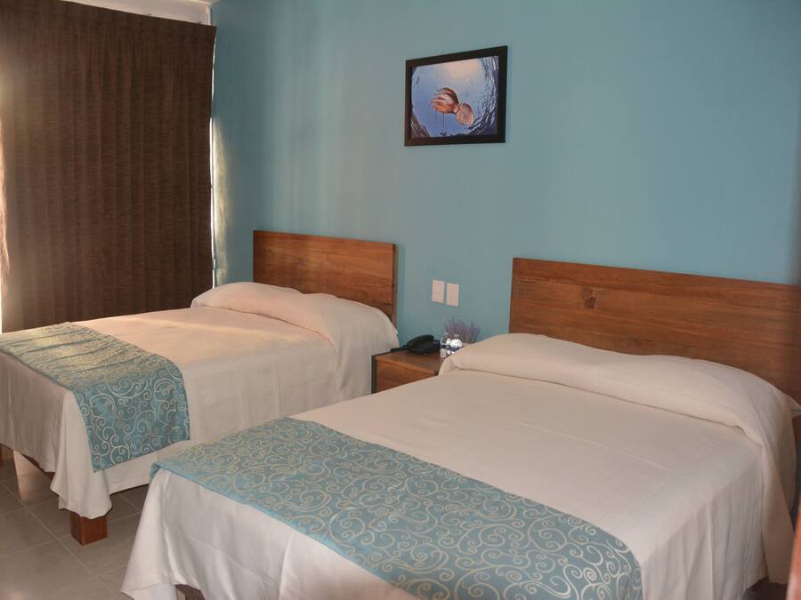 Two single beds with wooden headboards, a nightstand with a phone and a small vase, and a painting on the wall.