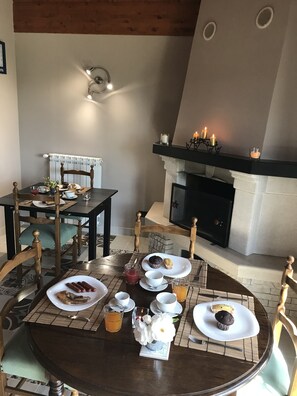 A dining area with a fireplace, a table set with plates of food, cups, and a vase of flowers. - La Collina delle Fonti (Aprilia)