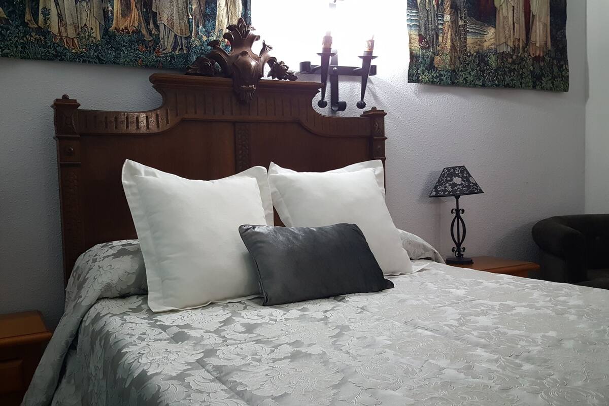 A neatly made bed with a floral-patterned bedspread and two pillows, flanked by two nightstands with lamps.