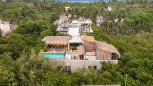 Un resort con piscina, estructuras de techo de paja y vistas al océano.