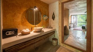 Un baño con un espejo grande, un lavamanos, una radio y una cesta de toallas.