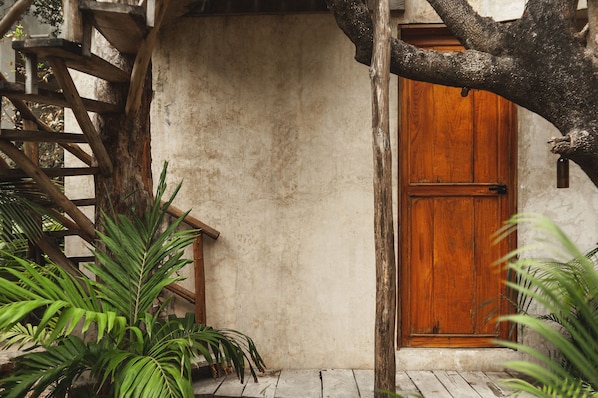 A rustic wooden door with a metal handle, a concrete wall, and a wooden staircase. - Casa Coyote Tulum (Tulum)