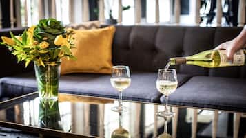 Una mesa de vidrio con dos copas de vino y una botella de vino sirviéndose en una de ellas.