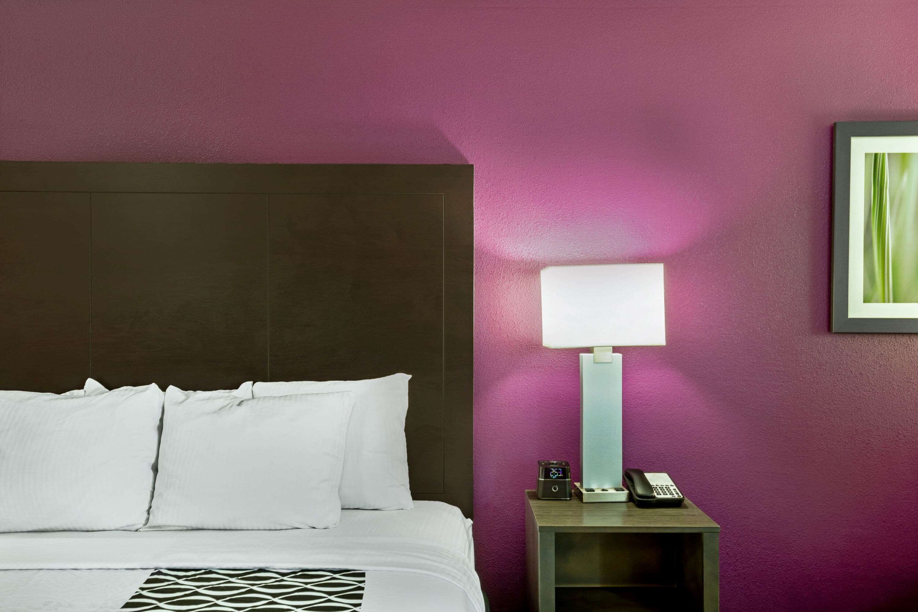 Une chambre d’hôtel avec un lit, une table de chevet, une lampe et un tableau encadré au mur.