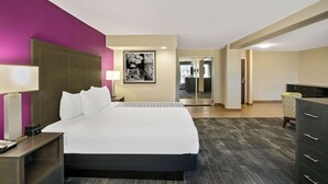 A hotel room with a bed, a desk, a chair, a dresser, and a painting on the wall. - La Quinta Inn & Suites by Wyndham Columbus MS (Columbus)