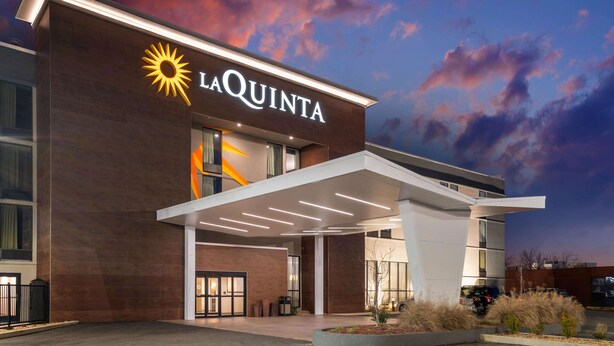 A modern hotel entrance with a prominent sun logo and the name 'LA QUINTA'. - La Quinta Inn & Suites by Wyndham Columbus MS (Columbus)