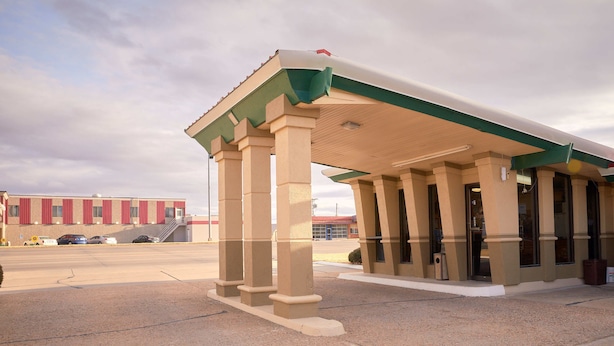 A building with a covered entrance, columns, and a parking lot. - South Wind Inn (Liberal)