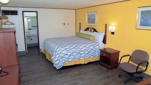 A hotel room with a bed, a desk, a chair, a dresser, and a mirror. - South Wind Inn (Liberal)