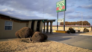 A Southwind Inn with a sign, columns, and a parking lot. - South Wind Inn (Liberal)
